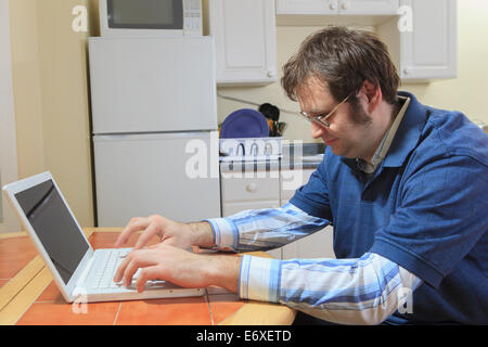 La tecnologia e l'ingegnere programmatore con Aspergers lavorando sul suo computer portatile da casa Foto Stock