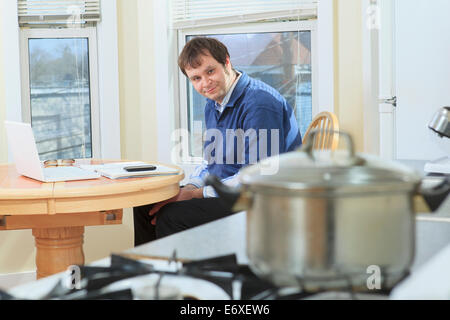 Uomo con Aspergers lavora nella sua casa durante la cottura Foto Stock