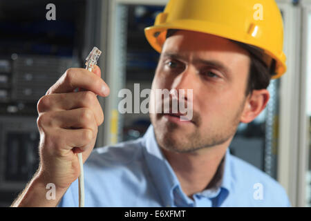 Ingegnere di rete esaminando con cavo a crimpare Foto Stock