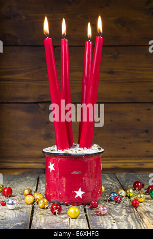 Rosso quattro candele di natale su uno sfondo di legno vecchio con le palle di Natale - vintage o in stile country Foto Stock