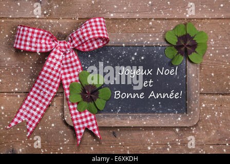 Chalk board con buon Natale Messaggio , santa e fiocchi di neve su sfondo di legno in francese con un rosso a scacchi con nastro Foto Stock