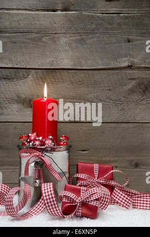 Natale in legno sfondo con una candela rossa e una confezione regalo sulla neve Foto Stock