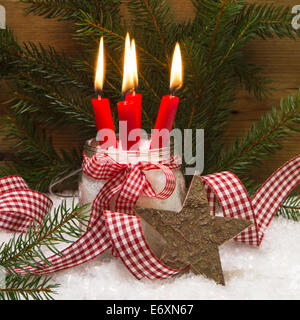 Square Natale carta decorata con quattro red candele accese, stella di legno, neve, nastro e ramo di pino Foto Stock