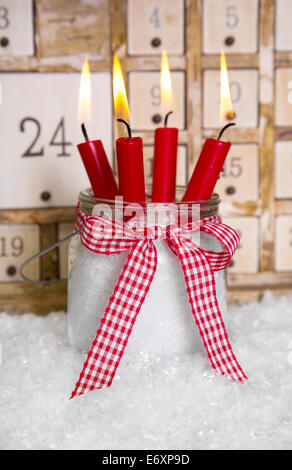 La vigilia di Natale: rosso quattro candele accese con una squallida avvento bianco sullo sfondo del calendario Foto Stock