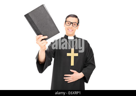 Felice giovane sacerdote tenendo una Sacra Bibbia isolati su sfondo bianco Foto Stock