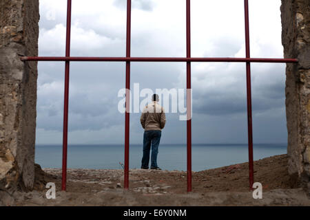 Uomo che guarda oltre lo stretto di Gibilterra dal Borj Dar el-Baroud, Tangeri, Marocco Foto Stock