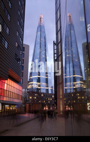 La Shard riflettendo nelle finestre dei moderni edifici per uffici di più luogo di Londra. Luci al neon brillare sul bagnato marciapiedi. Londra, Inghilterra, Regno Unito. Foto Stock