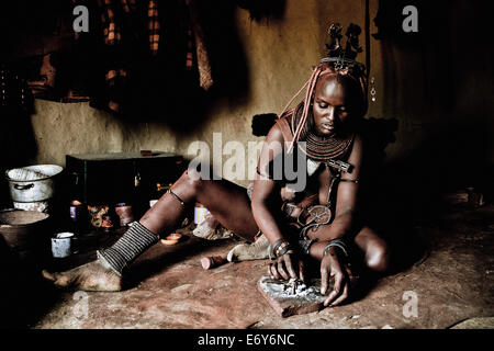 Donna della tribù Himba nel suo rifugio nella preparazione degli alimenti, Kaokoland, Namibia, Africa Foto Stock