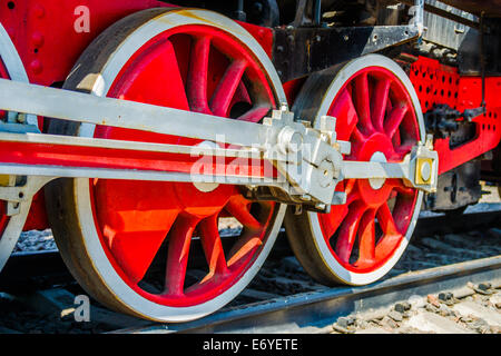 Primo piano delle ruote rosse e aste di guida di un antico treno a vapore Foto Stock