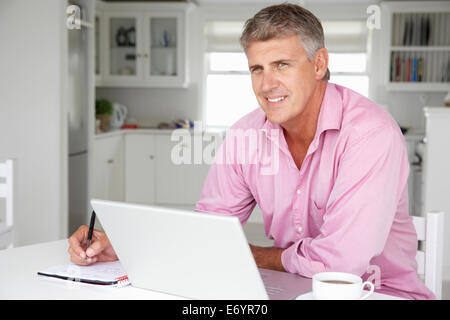 Età media uomo al lavoro sul portatile a casa Foto Stock