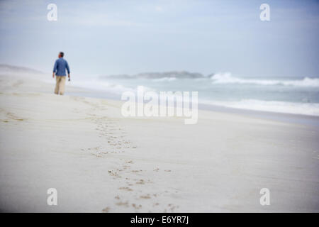 Senior uomo a camminare sulla spiaggia Foto Stock