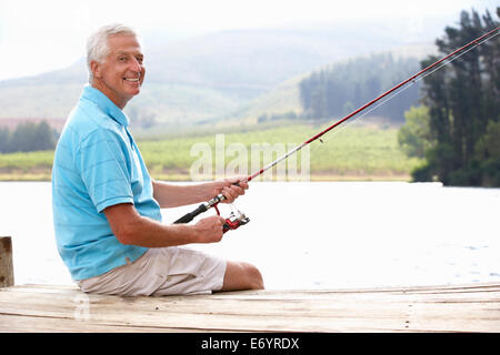 Uomo senior di pesca sul molo Foto Stock