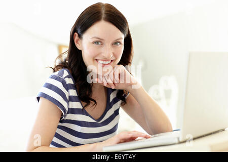 Donna che utilizza portatile a casa Foto Stock
