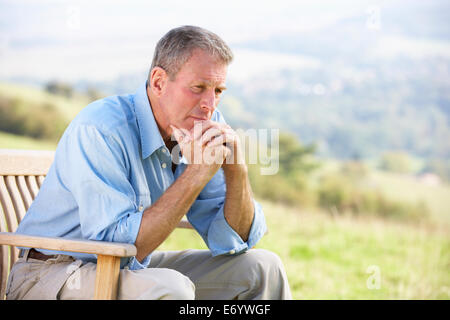Senior uomo seduto all'aperto Foto Stock