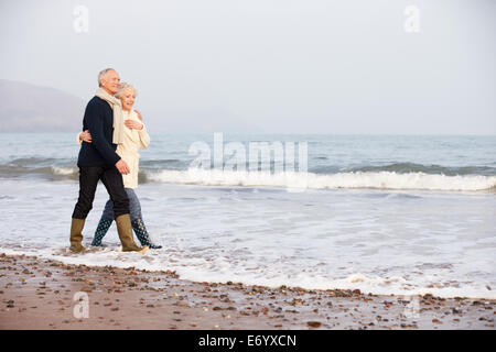 Coppia senior camminando lungo la Spiaggia Invernale Foto Stock