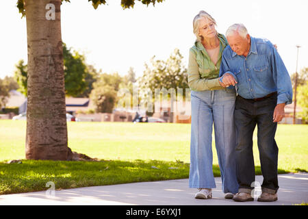 Senior donna aiutando il marito in quanto a Piedi nel Parco insieme Foto Stock