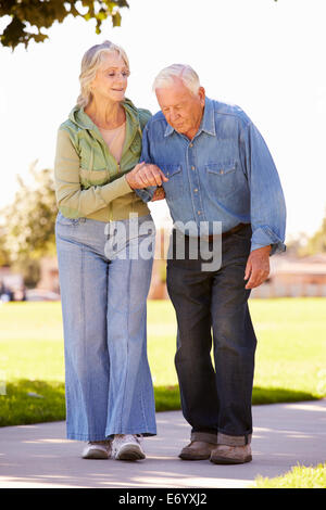 Senior donna aiutando il marito in quanto a Piedi nel Parco insieme Foto Stock