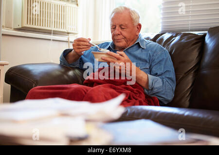 Senior Uomo con dieta povera di mantenere caldo sotto coperta Foto Stock