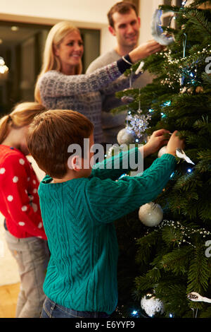 Famiglia decorare albero di Natale a casa insieme Foto Stock