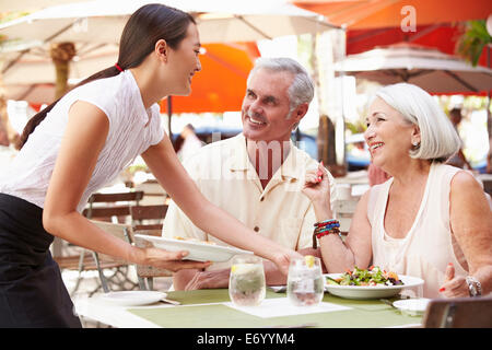 Cameriera serve coppia Senior il pranzo in un ristorante esterno Foto Stock