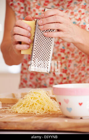 Close up donna grattugiare il formaggio in cucina Foto Stock