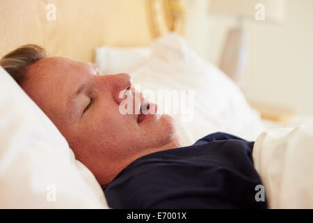 Il sovrappeso uomo addormentato nel letto il russamento Foto Stock