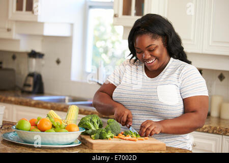 Donna sovrappeso preparare verdure in cucina Foto Stock