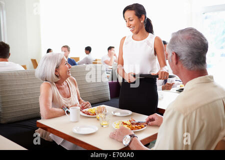 Cameriera serve coppia Senior Prima colazione in Hotel Ristorante Foto Stock