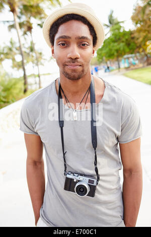 Ritratto di giovane uomo che porta la fotocamera Foto Stock