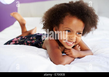 Carino Bambina giacente sulla pancia in letto con i genitori Foto Stock