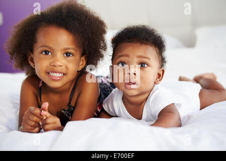 La suora con Baby fratello sdraiato sul letto con i genitori Foto Stock