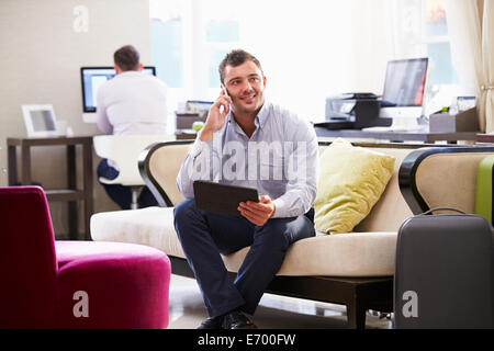 Imprenditore lavora su tavoletta digitale nella Hall Hotel Foto Stock