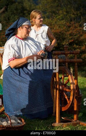 Una donna in tradizionale Beskid alpinisti costume dimostrando ruota di filatura. Foto Stock