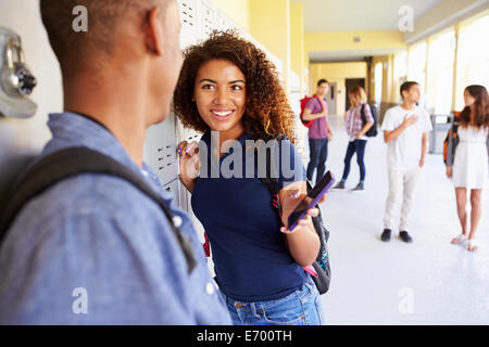 Gli studenti delle scuole superiori di armadietti guardando al telefono cellulare Foto Stock