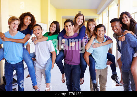 Un gruppo di studenti di scuola superiore dando piggyback in corridoio Foto Stock