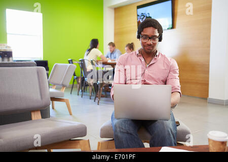 Lavoratore di sesso maschile con cuffie che lavora in un ufficio in loco di  un magazzino utilizzando clienti di consulenza per computer portatili Foto  stock - Alamy