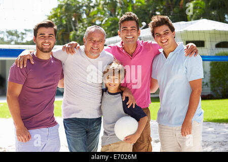 Maschio di generazione Multi Family giocando a pallavolo in giardino Foto Stock