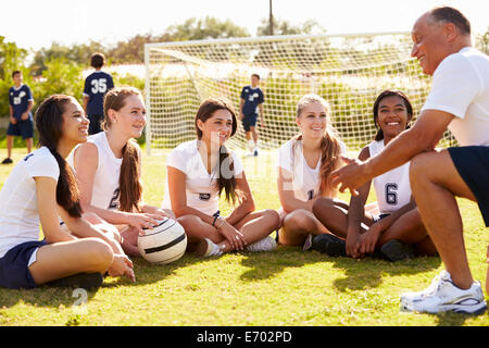 Allenatore dando Team parlare alle femmine di alta scuola calcio Team Foto Stock