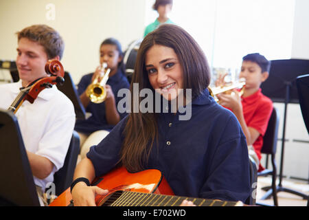 Pupilla d femmina a suonare la chitarra in alta scuola Orchestra Foto Stock