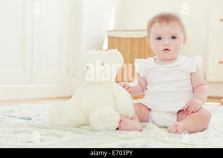Ritratto bambina e orsacchiotto seduto sul pavimento Foto Stock