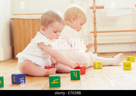 Baby sorelle giocando sul pavimento con la costruzione di blocchi Foto Stock