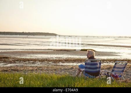 Senior donna a rilassarci in spiaggia Foto Stock