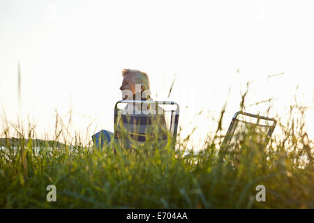 Senior donna a rilassarci in spiaggia Foto Stock