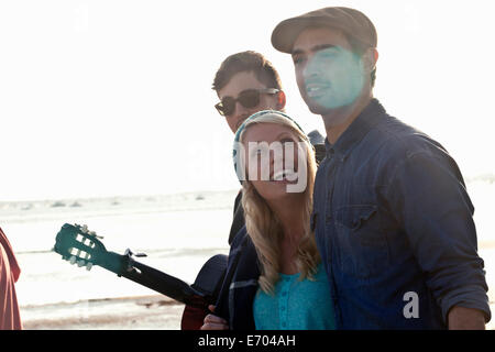 Tre amici adulti con la chitarra acustica sulla spiaggia di Bournemouth Dorset, Regno Unito Foto Stock