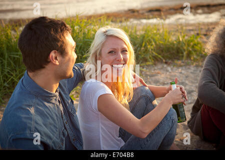 Tre amici adulti bere birra sulla spiaggia di Bournemouth Dorset, Regno Unito Foto Stock