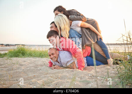 Gruppo di amici facendo pila umana sulla spiaggia Foto Stock