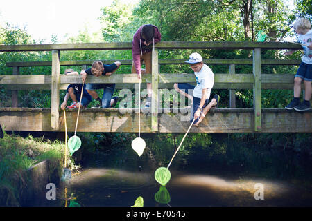 I ragazzi utilizzano reti da pesca sul ponte Foto Stock