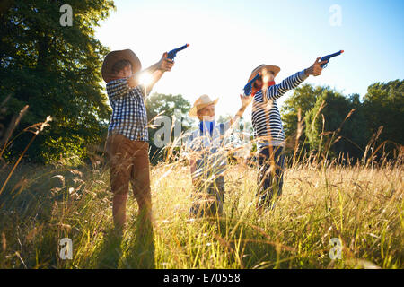 Tre giovani ragazzi vestito da cowboy, tenendo pistole giocattolo Foto Stock