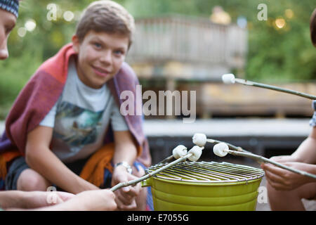 Gruppo di ragazzi tostare marshmallows su barbecue della benna Foto Stock