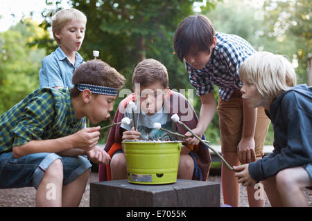 Gruppo di ragazzi tostare marshmallows su barbecue della benna Foto Stock